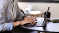 Businessperson hands typing on tablet keyboard on round table in meeting room