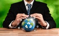 Businessperson holding and protecting Earth with recycle symbol. Reliance