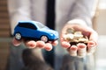 Businessperson Holding Small Blue Car And Golden Coins Royalty Free Stock Photo