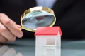 Businessperson Looking At House Model Through Magnifying Glass Royalty Free Stock Photo