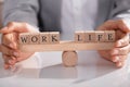 Businessperson Protecting Life And Work On Wooden Seesaw