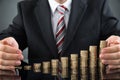 Businessperson Protecting Stack Of Coins