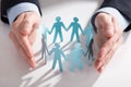 Businessperson`s Hand Protecting Paper Cut Out Figures Royalty Free Stock Photo