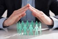 Businessperson`s Hand Protecting Paper Cut Out Figures Royalty Free Stock Photo