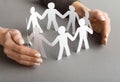 Businessperson`s hand protecting paper cut out figures Royalty Free Stock Photo