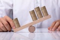 Businessperson Showing Unbalance Between Stacked Coins