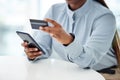 Businessperson using a credit card and phone to shop online at work. One person paying for a purchase using their Royalty Free Stock Photo