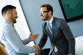 Businesss and office concept - two businessmen shaking hands in office