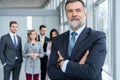 Businessteam in office, Happy Senior Businessman in His Office is standing in front of their team. Royalty Free Stock Photo