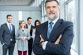 Businessteam in office, Happy Senior Businessman in His Office is standing in front of their team. Royalty Free Stock Photo