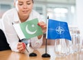 Businesswoman arranging the flags of NATO (OTAN) and Pakistan for presentation and negotiations