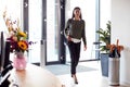 Businesswoman Arriving For Work At Office Walking Through Door