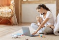 Businesswoman with baby boy working from home using laptop, phone Royalty Free Stock Photo