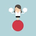 Businesswoman balancing on red ball holding two spheres