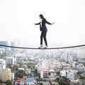 Businesswoman balancing on a string over the city, city view with scyscrapers in the background. Risk and self confidence concept Royalty Free Stock Photo