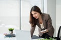 A businesswoman bending over a table, holding a calculator, and using her laptop Royalty Free Stock Photo