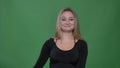 Businesswoman in black blouse gesturing dubbing into camera happily at green background.