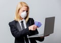 Businesswoman in black suit and face mask with money and computer