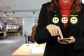 Businesswoman in black suit pressing smiling face and five stars emoticon on mobile phone for evaluation and rating customer