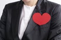 A businesswoman in a black suit and a red heart. The concept of charity and kindness