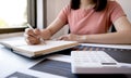 Businesswoman bookkeeper hand note analysis the graph with calculator and laptop at the home office for setting challenging