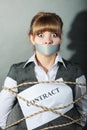 Businesswoman bound by contract with taped mouth.