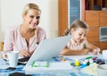 Businesswoman browsing internet at home, daughter drawing in pencil Royalty Free Stock Photo