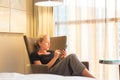 Businesswoman on business travel, tired from business meeting, sitting alone in hotel room afterwork, reading and Royalty Free Stock Photo