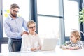 Businesswoman and businessman with eyeglasses working with laptop daughter drawing near in office Royalty Free Stock Photo