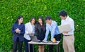 Businesswoman and businessman meeting outside office using laptop computer mobile phone and tablet device at green leaf Royalty Free Stock Photo