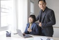 Businesswoman and businessman showing thumbs up sign with computer on wooden table in office background. Royalty Free Stock Photo