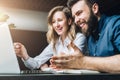 Businesswoman and businessman are sitting at desk against laptop and discussing business project, working together.