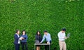 Businesswoman and businessman working outside office using laptop computer mobile phone and tablet device at green leaf Royalty Free Stock Photo