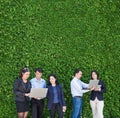 Businesswoman and businessman working outside office using laptop computer mobile phone and tablet device at green leaf Royalty Free Stock Photo