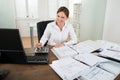 Businesswoman Calculating Financial Data At Desk
