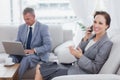 Businesswoman calling while her colleague working on his laptop Royalty Free Stock Photo