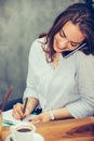 Businesswoman calling on mobile phone and taking notes Royalty Free Stock Photo