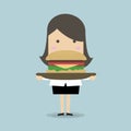 Businesswoman carrying a big hamburger with a beef patty and trimmings