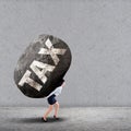 Businesswoman carrying a big rock of TAX Royalty Free Stock Photo