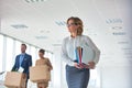 Businesswoman carrying files while colleagues talking with cardboard boxes at new office