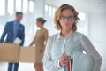 Businesswoman carrying files while colleagues talking with cardboard boxes at new office