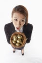 Businesswoman carrying a nest filled with gold eggs