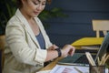 Businesswoman checking time and looking at smart wrist watch at home office.  Asian Woman seeing clock to work. Desk with laptop, Royalty Free Stock Photo