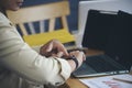 Businesswoman checking time and looking at smart wrist watch at home office.  Asian Woman seeing clock to work. Desk with laptop, Royalty Free Stock Photo