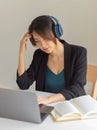 Businesswoman concentrating on her work while using headphone, laptop and book