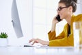 Businesswoman concentrating on work, using computer and cellphone in office Royalty Free Stock Photo