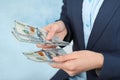 Businesswoman counting dollars on color background