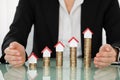 Businesswoman Covering House Models On Stacked Coins