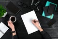 Businesswoman desk with with different objects. A woman`s hand writes in a notebook