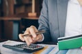 Businesswoman on desk in office using calculator to calculate saving account passbook and statement with financial report .Female Royalty Free Stock Photo